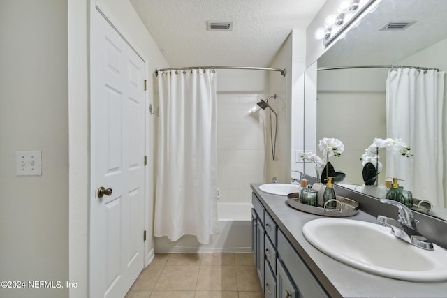 bathroom with tile patterned floors, shower / bath combo with shower curtain, vanity, and a textured ceiling