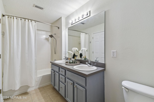 full bathroom featuring tile patterned flooring, shower / tub combo, toilet, vanity, and a textured ceiling