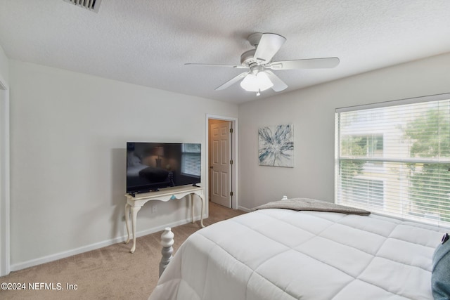 carpeted bedroom featuring ceiling fan and a textured ceiling