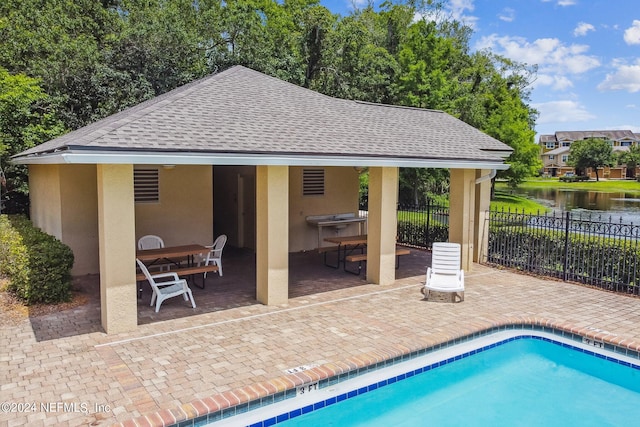 view of pool with a water view and a patio area