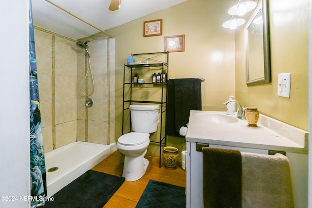 bathroom with toilet, wood-type flooring, walk in shower, vanity, and ceiling fan