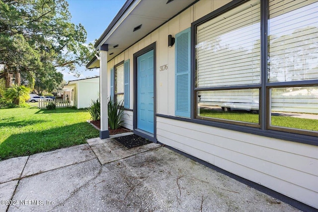 property entrance with a patio area and a lawn