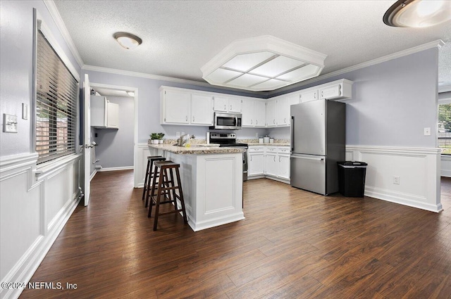 kitchen with stainless steel appliances, a center island, white cabinets, a textured ceiling, and dark hardwood / wood-style flooring