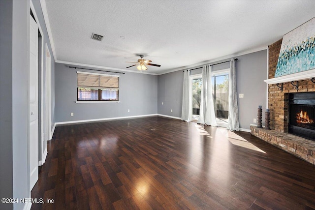 unfurnished living room featuring dark wood-type flooring, crown molding, a healthy amount of sunlight, and a fireplace