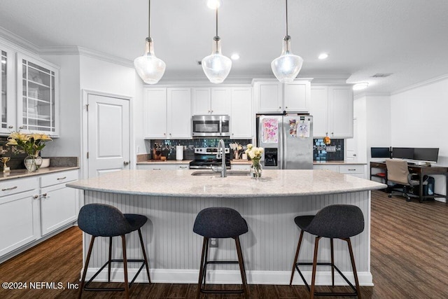 kitchen featuring dark hardwood / wood-style flooring, stainless steel appliances, a center island with sink, white cabinetry, and a breakfast bar area