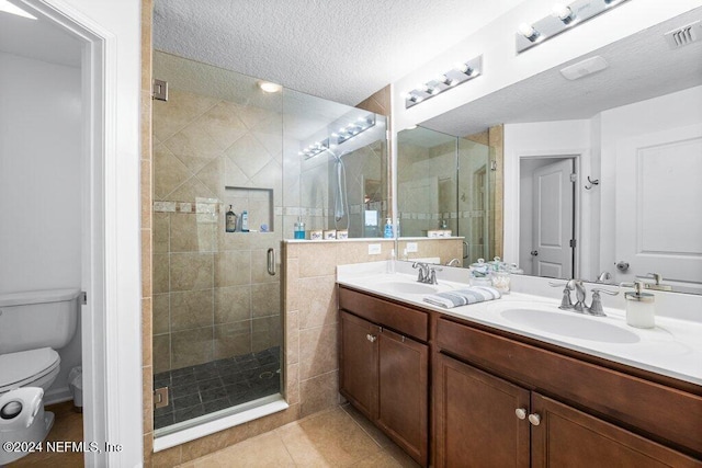 bathroom featuring tile patterned floors, an enclosed shower, a textured ceiling, toilet, and vanity