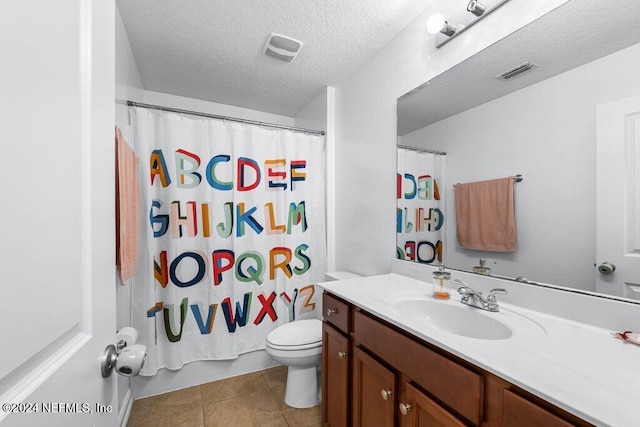 bathroom with tile patterned flooring, vanity, a textured ceiling, and toilet