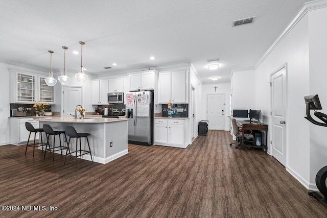 kitchen featuring appliances with stainless steel finishes, dark wood-type flooring, white cabinetry, a kitchen island, and hanging light fixtures