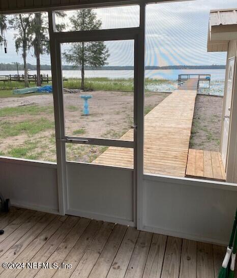 doorway featuring light wood-type flooring, a water view, and a wealth of natural light