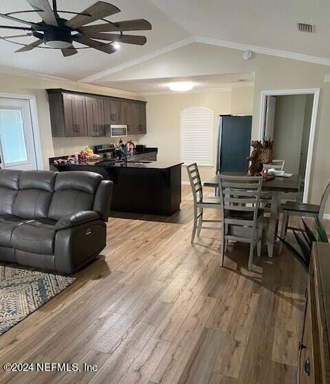 living room with lofted ceiling, crown molding, ceiling fan, and light wood-type flooring