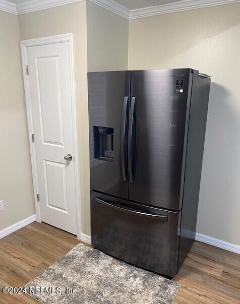 room details featuring ornamental molding, light hardwood / wood-style floors, and stainless steel refrigerator with ice dispenser