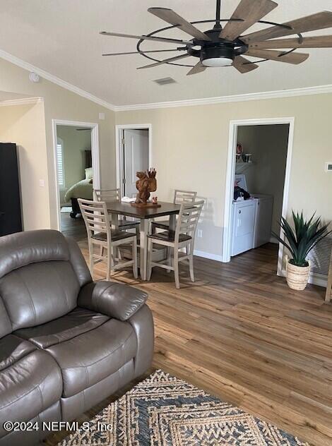 living room featuring dark wood-type flooring, ceiling fan, ornamental molding, and washer and clothes dryer