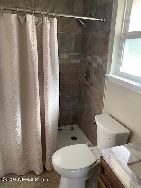 bathroom with walk in shower, vanity, and toilet