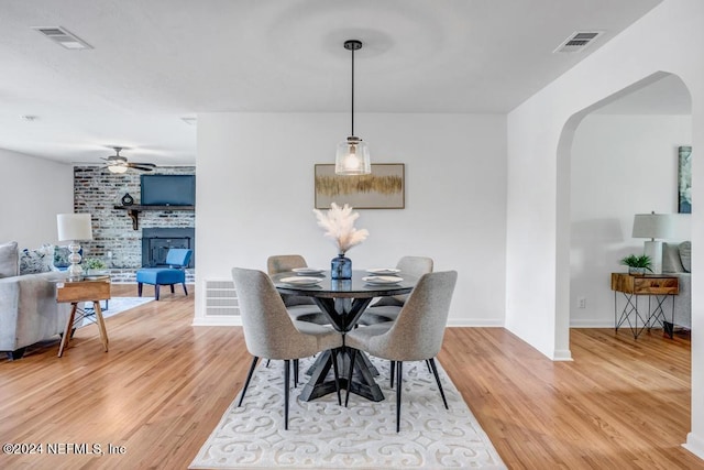 dining space featuring a fireplace, ceiling fan, and hardwood / wood-style floors