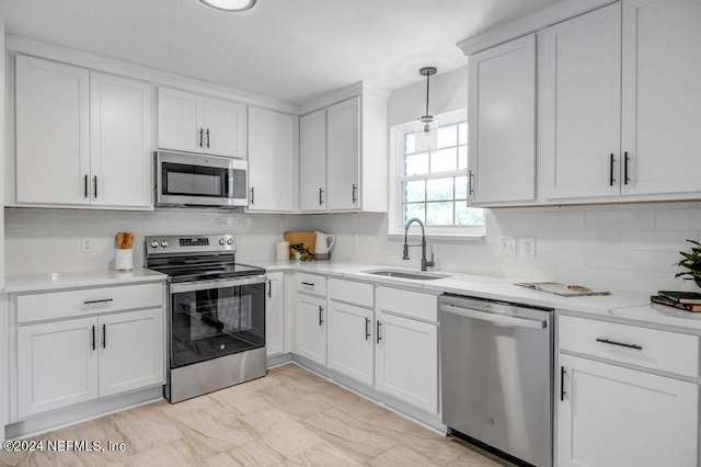 kitchen featuring decorative light fixtures, appliances with stainless steel finishes, sink, and white cabinetry