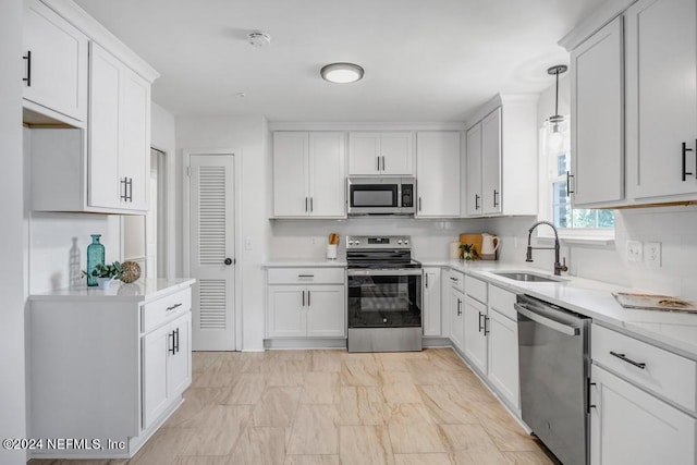 kitchen with pendant lighting, appliances with stainless steel finishes, sink, and white cabinetry