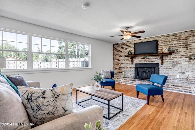 living room featuring brick wall, hardwood / wood-style flooring, a textured ceiling, and ceiling fan