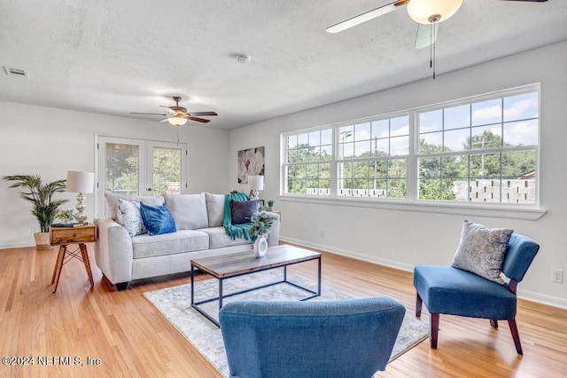 living room featuring ceiling fan, light hardwood / wood-style floors, and a healthy amount of sunlight