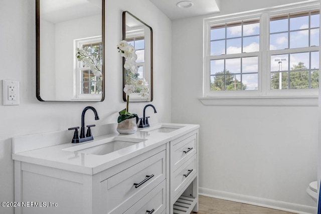 bathroom featuring vanity, toilet, and a healthy amount of sunlight