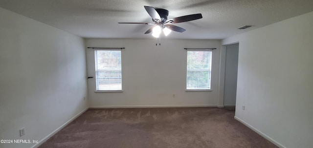 carpeted spare room featuring ceiling fan and a textured ceiling