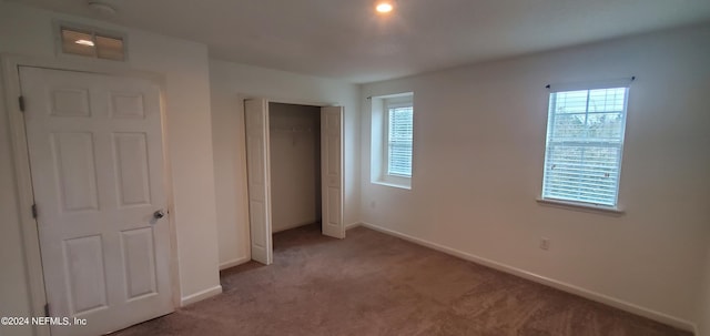 unfurnished bedroom featuring light colored carpet and a closet