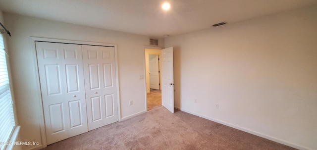 unfurnished bedroom featuring a closet and light colored carpet