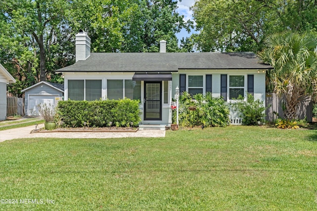 view of front of house with a garage, an outbuilding, and a front lawn