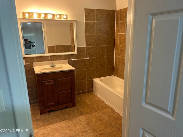 bathroom featuring tile patterned flooring, a bathtub, vanity, and tile walls