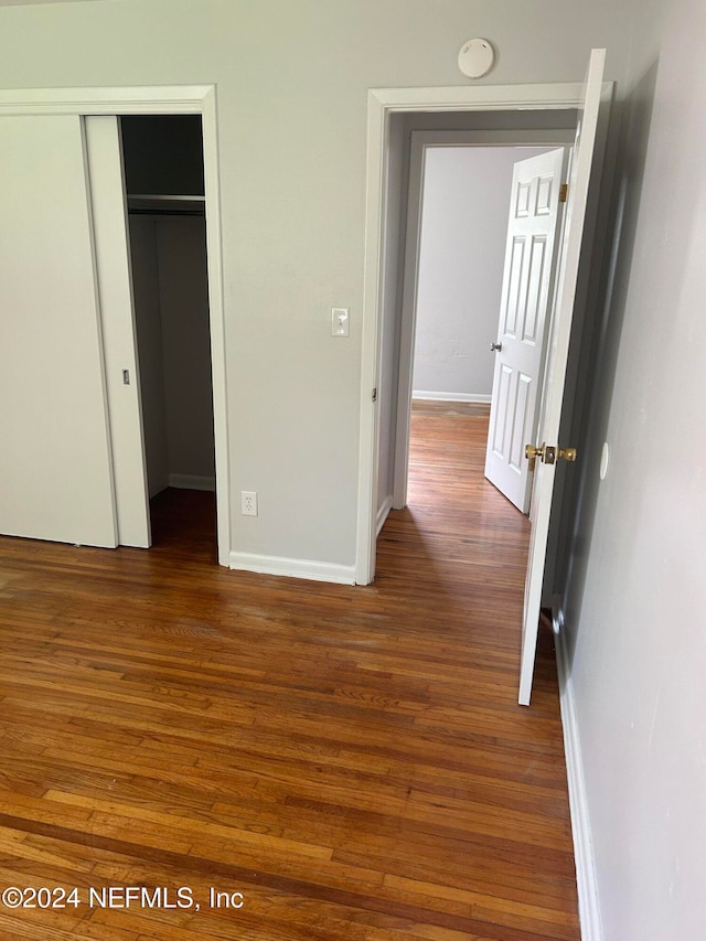 unfurnished bedroom with a closet and dark wood-type flooring