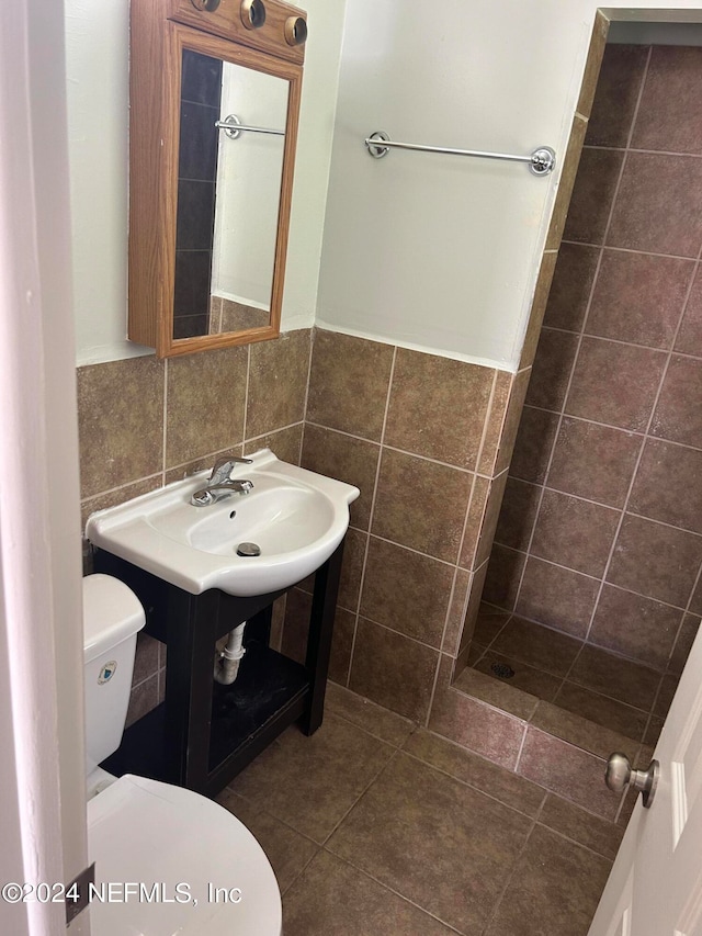 bathroom featuring tile patterned flooring, tile walls, walk in shower, and toilet