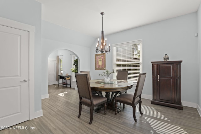 dining room featuring hardwood / wood-style floors, a chandelier, and vaulted ceiling