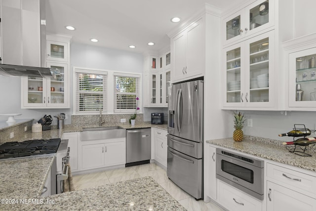 kitchen featuring range hood, sink, appliances with stainless steel finishes, and white cabinetry