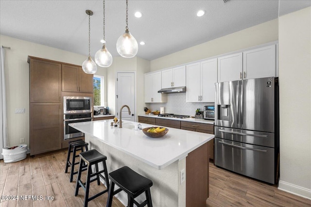 kitchen featuring a center island with sink, stainless steel appliances, hardwood / wood-style floors, and sink