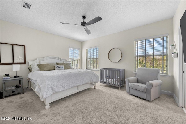 carpeted bedroom featuring multiple windows, ceiling fan, and a textured ceiling