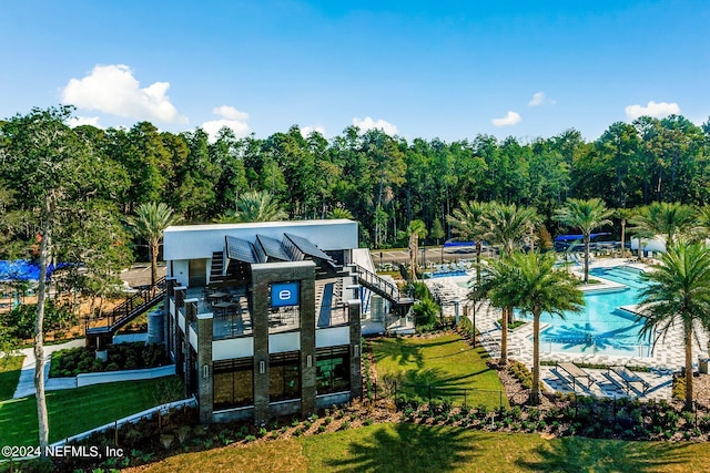 rear view of house featuring a community pool and a lawn