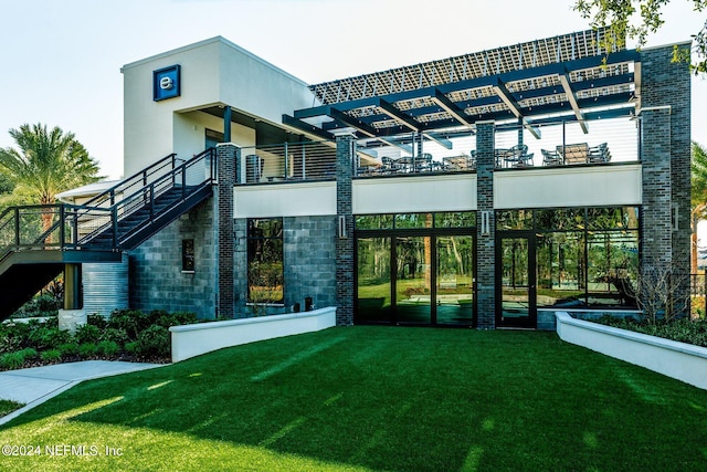 back of house featuring a lawn and a balcony