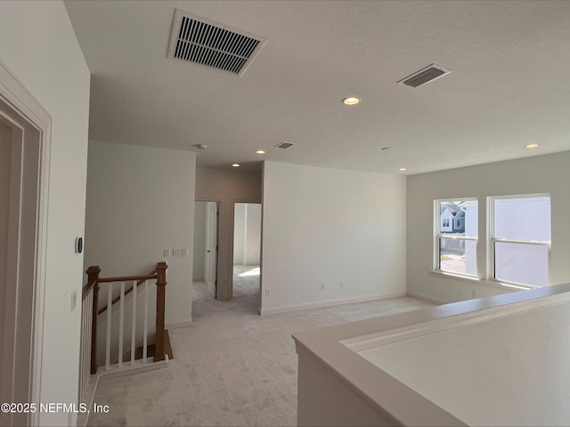 empty room featuring a textured ceiling and light colored carpet