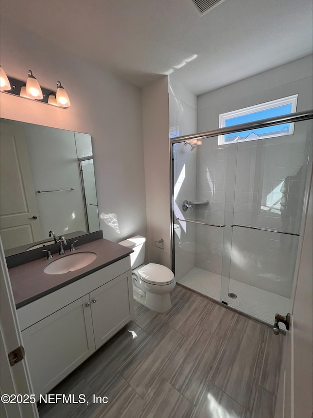 bathroom featuring vanity, toilet, and a shower with shower door