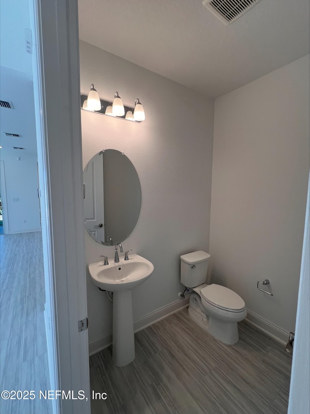 bathroom with hardwood / wood-style flooring and toilet