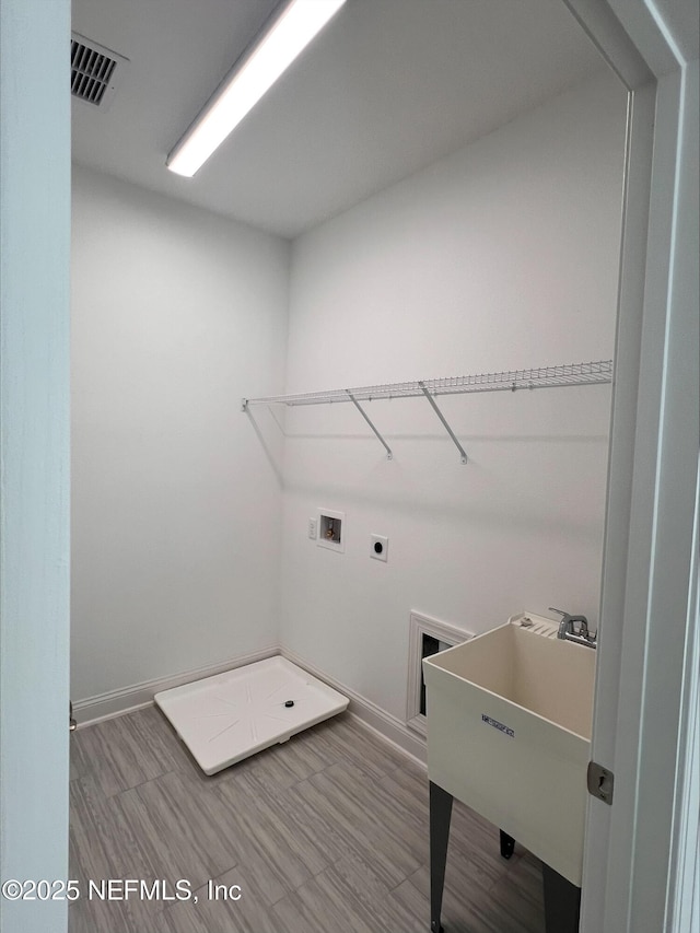 clothes washing area featuring sink, washer hookup, hookup for an electric dryer, and hardwood / wood-style floors