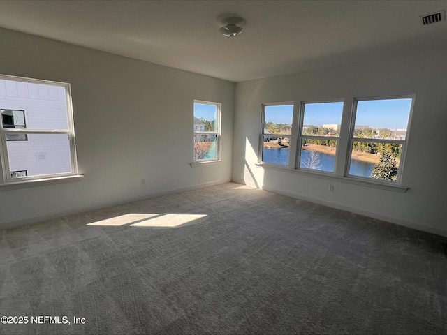 unfurnished room featuring a water view and carpet