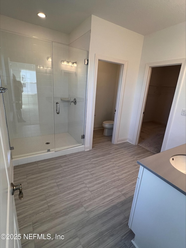 bathroom featuring vanity, toilet, and a shower with door