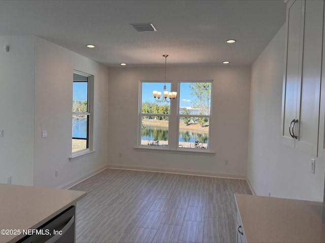 unfurnished dining area featuring a notable chandelier, a water view, and a healthy amount of sunlight