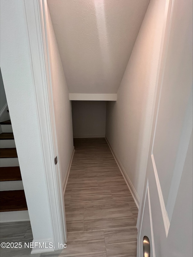 hall with a textured ceiling and lofted ceiling