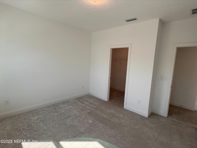 unfurnished bedroom featuring carpet flooring, a spacious closet, and a closet