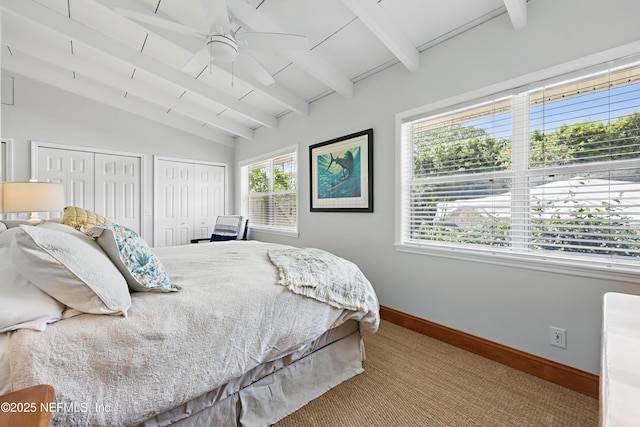 bedroom featuring a ceiling fan, baseboards, lofted ceiling with beams, multiple closets, and carpet flooring
