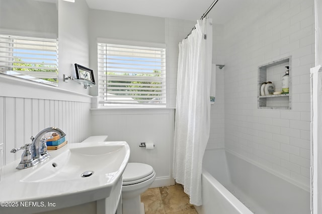 full bathroom with a sink, wainscoting, shower / bath combination with curtain, and toilet