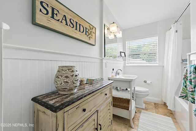 bathroom featuring wainscoting and toilet