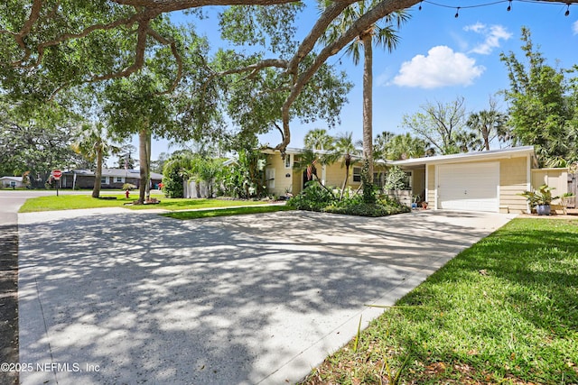 view of front of house featuring an attached garage, driveway, and a front lawn