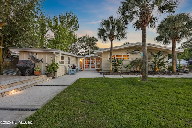 mid-century modern home featuring a wooden deck, a patio, and a front yard